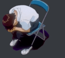 a man is sitting on a blue chair with his head down .