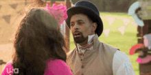 a man in a top hat is talking to a woman in a pink shirt with usa on the bottom