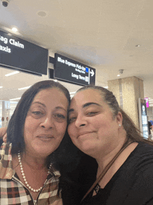 two women posing for a picture in front of a sign that says blue express pick up