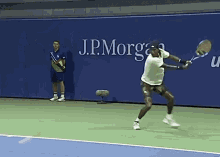 a tennis player swings his racket in front of a j.p. morgan wall