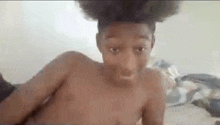 a shirtless young man with an afro is taking a selfie .