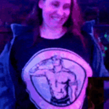 a woman wearing a shirt with a picture of a man on it is sitting in a dark room .