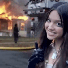 a woman is holding a gun in front of a burning building .