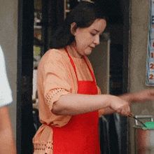 a woman wearing a red apron is preparing food in front of a calendar with the number 2 on it