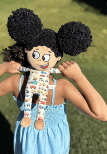 a little girl in a blue dress is holding a stuffed doll