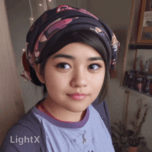 a woman wearing a head scarf and a lightx shirt looks at the camera