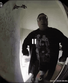 a man wearing glasses and a black jacket is standing in front of a doorbell camera .