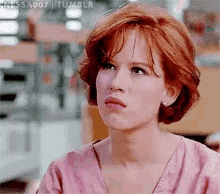 a woman with red hair is making a funny face while wearing a pink shirt .