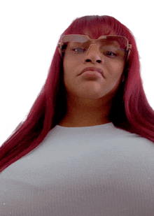 a woman with red hair wearing sunglasses looks at the camera