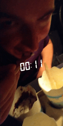 a person eating ice cream with a digital clock that says 00:11