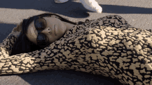 a woman wearing sunglasses is laying on the ground with a bandage on her face