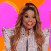 a woman wearing a silver jacket and red lipstick smiles for the camera