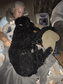 a man is laying on a couch with two black dogs and an oxygen machine in the background