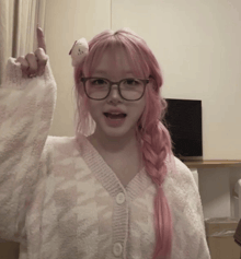 a girl with pink hair and glasses holds up her finger