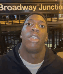 a man is standing in front of a sign that says broadway junction