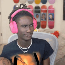a young man wearing pink headphones and a necklace with the word jesus on it