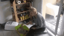 a woman is kneeling down next to a litter box with a container that says ' noodles ' on it