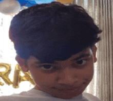 a young boy is making a funny face in front of balloons and a window .