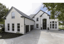 a large white house with a black garage door and a driveway