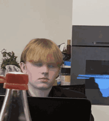 a young man sitting in front of a laptop with a bottle in front of him that says ' coca cola ' on it