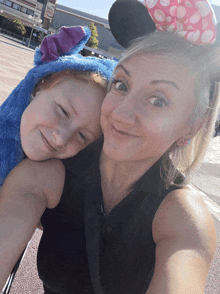 a woman and child wearing minnie mouse ears pose for a photo