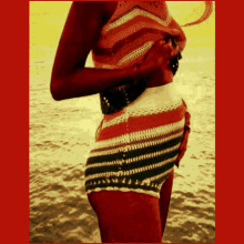 a woman in a striped top and shorts stands on the beach