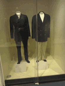 two men 's suits are displayed in a glass case with a sign that says ' military ' on it