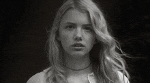 a black and white photo of a young woman with long blonde hair and a choker .