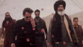 a group of men are walking in the desert with roses falling from the sky .