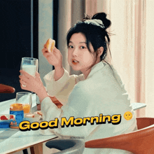 a woman sitting at a table holding a glass of milk and a piece of bread with the words " good morning " above her