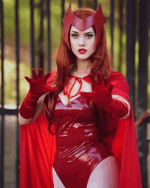 a woman is wearing a scarlet witch costume and gloves .