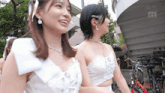 a woman in a white dress is smiling next to another woman in a black dress