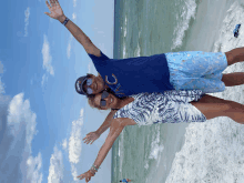 a man wearing a blue shirt with the letter c on it stands next to a woman on the beach