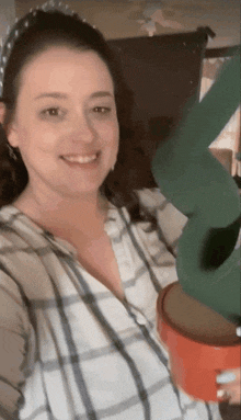 a woman in a plaid shirt is holding a red pot