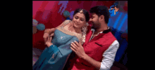 a man in a red vest is holding a woman in a blue dress