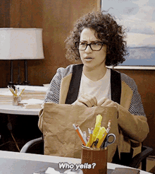 a woman sitting at a desk with a bag of pencils and scissors and the words who yells behind her