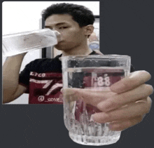 a man is drinking water from a bottle while holding a glass with the number 88 on it