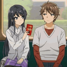 a boy and a girl are sitting next to each other on a train . the girl is holding a pack of pocky .