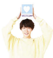 a man in a yellow sweater is holding a block with a heart on it