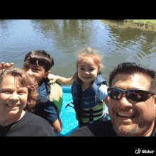 a family posing for a picture in a boat with a girl wearing a life vest that says x on it