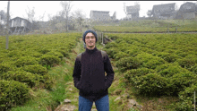 a man in a black jacket stands in a field