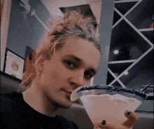 a woman is holding a margarita in her hand and taking a selfie .