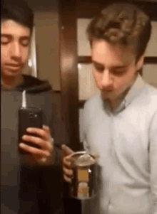 two young men are taking a picture of themselves in a mirror .