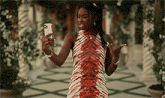 a woman in a red and white zebra print dress is taking a selfie with her phone .
