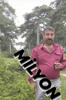 a man in a pink shirt stands in front of a tree with the word milyon written on the bottom