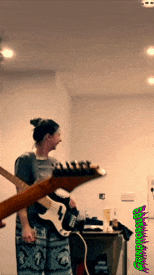 a person playing a guitar in front of a wall that has a green sticker that says ' grindcore '