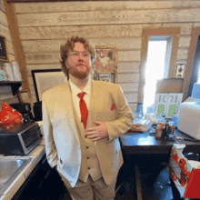 a man in a tan suit and red tie