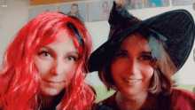 two women with red hair and black hats are posing for a picture together