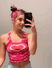 a girl with pink hair is taking a picture of herself with her phone