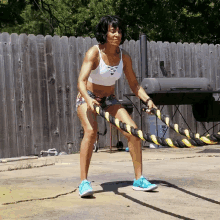 a woman in a white tank top is holding a rope